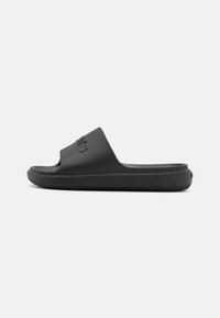 Sorte flip-flops lavet af tekstureret gummi med en bred rem og rillet sål, der har et logo på oversiden.