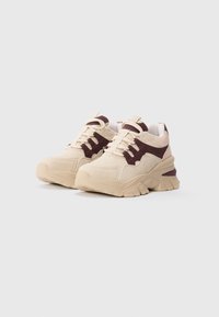 Pair of beige and dark brown chunky sneakers with thick soles and lace-up fronts on a plain light background.