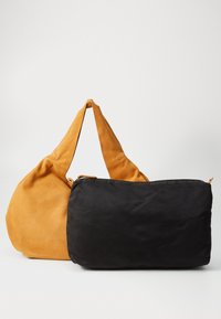 Two bags displayed: a mustard yellow suede hobo bag with a wide strap, and a black fabric pouch with a smooth finish and zipper.