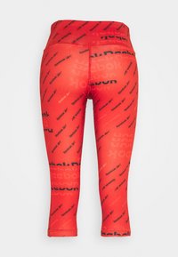 Červené legíny se všudypřítomným černým logem "Reebok" a abstraktními textovými vzory. Vyrobeny z pružného materiálu, zkrácená délka a přiléhavý střih.