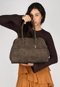 Bolso de mano de cuero sintético marrón con un diseño estructurado, doble asa superior, costuras acentuadas y un detalle de hebilla en tono dorado.