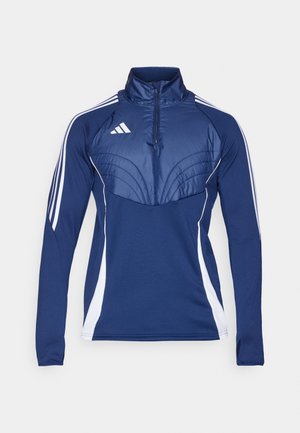Maglietta sportiva blu navy con colletto a mezza zip, pannelli laterali bianchi e dettagli a pannello testurizzati sul petto. Presenta il logo Adidas sul lato sinistro.