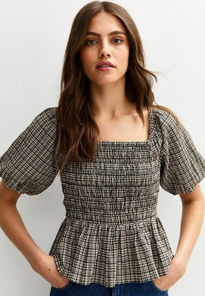 Gerimpelde zwart-wit geblokte blouse met korte pofmouwen en een peplumzoom. Heeft een vierkante halslijn en een textuurstof.