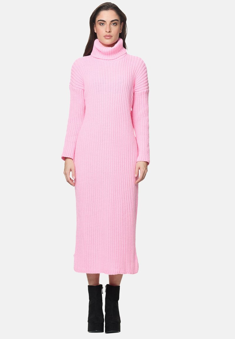 Langärmliges, Rollkragenkleid aus geripptem Strick, in einem hellen Pinkton, knielanges Design und eine taillierte Silhouette, kombiniert mit schwarzen Knöchelstiefeln.