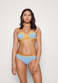 Conjunto de biquíni em tecido azul claro com detalhes laranja, desenhado com um laço ao centro e alças ajustáveis.