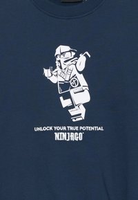 Navyblaues Sweatshirt mit einem weißen Grafikdesign eines LEGO-Ninja-Charakters und dem Text "ENTFESSEL DEINEN WAHREN POTENZIAL NINJAGO" darunter.