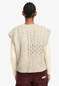Light gray knitted vest with a cable pattern, short sleeves, and a round neckline, paired with a cream long-sleeve shirt.