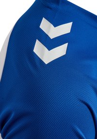 Blå atletisk skjorte lavet af åndbart mesh-stof. Har store hvide chevron-logoer på fronten med kontrasterende hvide ærmer.