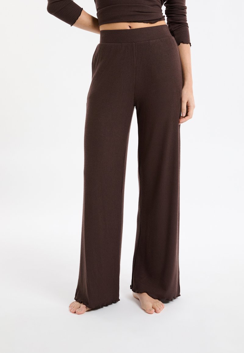 Braune, gerippte Strickhose mit hohem Bund, weitem Bein und ausgefranstem Saum, aus weichem Stoff. Keine sichtbaren Verzierungen.