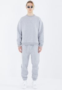 Grau Sweatshirt- und Jogginghosen-Set aus weichem Stoff. Der Pullover hat einen Rundhalsausschnitt und Rippbündchen; die Hose verfügt über einen elastischen Bund und Bündchen.