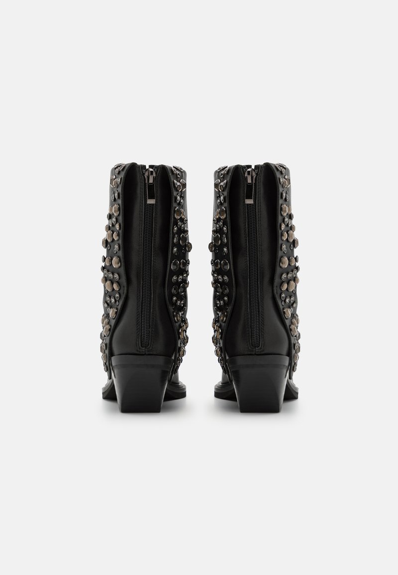 Botas negras de cuero hasta el tobillo con un tacón apilado, cremalleras laterales y tachuelas decorativas dispuestas en varios tamaños en los lados exteriores.