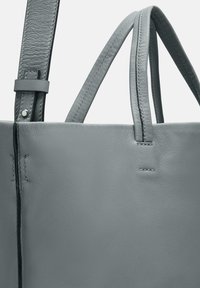 Grau Ledertasche mit glatter Textur, zwei oberen Griffen, flachem Design und sichtbaren Nähten entlang der Kanten.