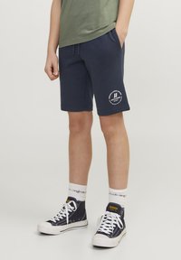 Shorts i bomullsblandning i marinblått med elastisk midja, sidofickor och en vit logografik på vänster ben. Kombineras med högskurna sneakers.