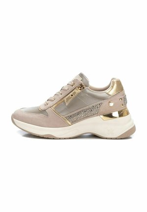 Zapatilla beige fabricada en ante y materiales sintéticos, con detalles metálicos dorados, adornos de strass y una suela blanca gruesa.