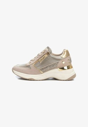 Beige sneaker crafted from suede and synthetic materials, featuring metallic gold accents, rhinestone detailing, and a chunky white sole.