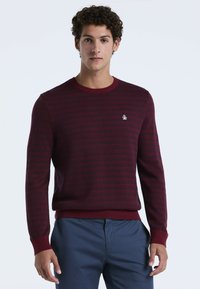 Burgunderfarbener Pullover mit strukturiertem Muster, Rundhalsausschnitt, gerippten Ärmeln und Saum. Mit einem kleinen gestickten Logo auf der Brust.