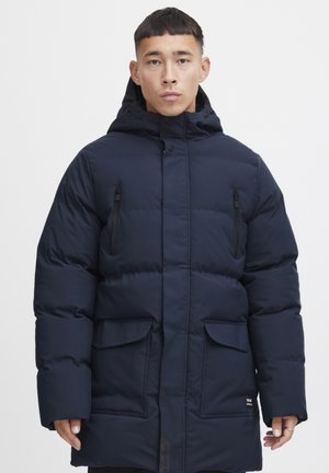 Navy blue padded parka with a hood, featuring a zippered chest pocket, front flap pockets, and a full-length zipper closure.