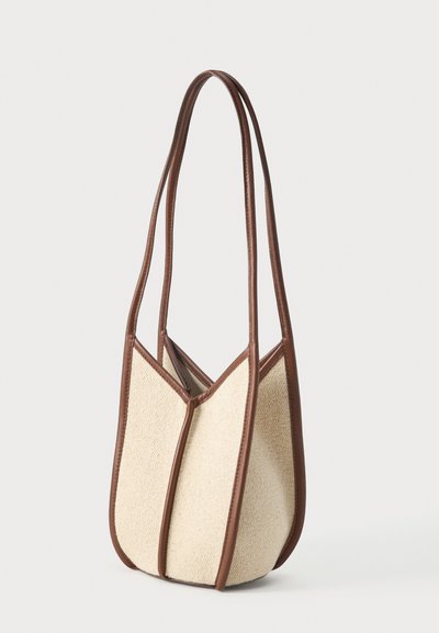 Beige gewebte Stoffhandtasche mit braunem Lederbesatz und zwei langen Schulterriemen, strukturiert mit vertikalen Lederkanten.