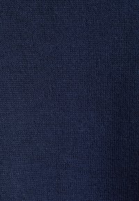 Gros plan d'un tissu tricoté bleu foncé montrant une texture détaillée et de fines boucles de fil.