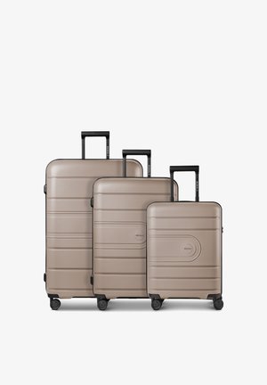 Drei beige Hartschalenkoffer in verschiedenen Größen mit schwarzen ausziehbaren Griffen und jeweils vier Rollen, von größtem zu kleinstem angeordnet.