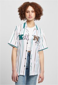Bijela prugasta majica s teal i smeškastim akcentima, sadrži dugmad, kratke rukave i višebojni natpis na prednjem delu.
