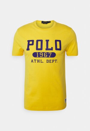 Gelbes T-Shirt mit kurzen Ärmeln und blauem Schriftzug „POLO 1967 ATHL. DEPT.“ auf der Vorderseite und einem kleinen Polo Ralph Lauren-Label nahe dem unteren Saum.