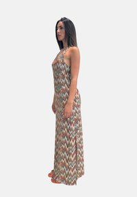 Abito lungo con un motivo zigzag multicolore in tonalità terrose, dotato di spalline sottili e una fessura laterale per facilitare i movimenti.