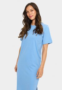 Abito azzurro chiaro a maniche corte con scollatura rotonda, taglio dritto e spacchi laterali per facilitare i movimenti. Tessuto morbido in misto cotone.