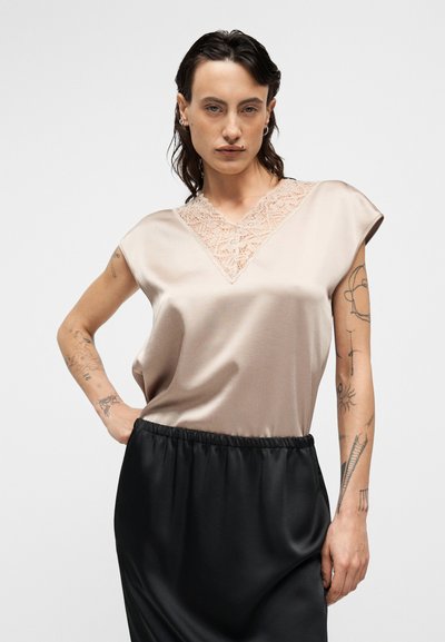 Μπεζ σατέν τοπ με V-λαιμόκοψη διακοσμημένη με δαντέλα, μανίκια καπέλο, συνδυασμένο με μαύρη σατέν φούστα. Λείο υλικό, απλός σχεδιασμός.