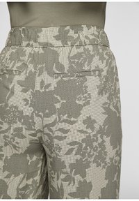 Pantalon à motif floral vert et beige avec une finition texturée, doté d'une taille et de deux poches arrière.