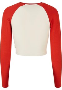 Rot- und cremefarbenes Langarmoberteil mit cropped Design, das im Raglan-Stil gehalten ist und eine weiche, glatte Textur aufweist. Einfarbiger Stoff ohne Muster.