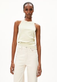 Lichtgroene, geribbelde tanktop met een ronde hals, gecombineerd met hooggewijze, off-white spijkerbroek. Gladde textuur; minimale details.