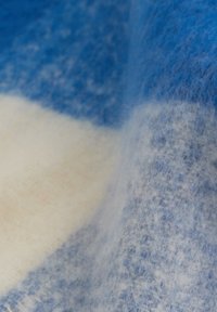 Blå och vit textil med en mjuk, fluffig känsla, som har en blandning av färger som skapar ett gradientmönster. Lätt och varmt tyg.