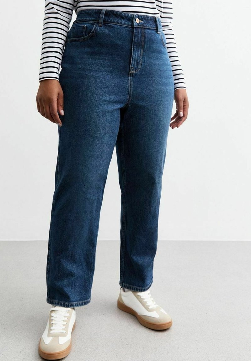 Jeans blu scuri a vita alta con una vestibilità dritta, dotati di chiusura con bottone anteriore e tasche frontali, abbinati a sneaker bianche.