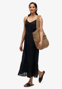 Czarna maxi sukienka z koronkowymi detalami, lekki materiał oraz rozkloszowany dół. Zestawiona z plecioną torbą na ramię i czarnymi sandałami.