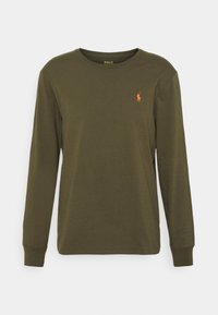 Zielona koszula z długim rękawem o okrągłym dekolcie i małym pomarańczowym logo polo na lewej piersi. Gładkie białe tło.