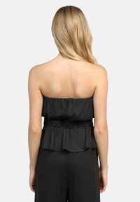 Top noir sans manches avec un ourlet à volants et une taille élastique, fabriqué dans un tissu léger. Texture lisse et design simple. Vue arrière montrée.