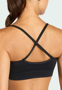 Μαύρο αθλητικό σουτιέν με υφή ριμπ, με σταυρωτές τιράντες στην πλάτη. Ο σχεδιασμός είναι μινιμαλιστικός, εστιάζοντας στην άνεση και την υποστήριξη.