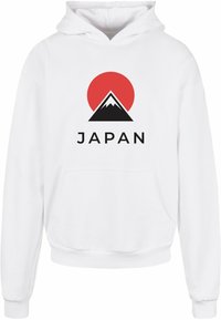 Fehér kapucnis póló, amelyen fekete hegycsúcs, piros kör és a "JAPAN" szó vastag fekete betűkkel látható. Klasszikus kenguru zseb kialakítás.