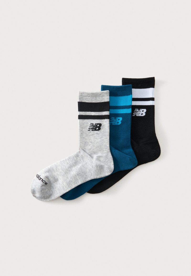 Τρεις κάλτσες New Balance σε γκρι, μπλε και μαύρο με αντίθετες ρίγες και λογότυπο σε λευκό φόντο.