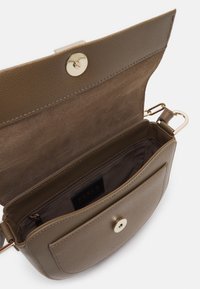 Hnědá kožená taška přes tělo s hladkým povrchem, zlatými kovovými doplňky a klopou. Uvnitř se nachází hlavní kapsa a zipová kapsa.