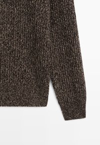 Brązowy sweter dzianinowy z teksturowym wzorem i ściągaczami u mankietów. Posiada lekko otwarty boczny szew dla swobodnego kroju.