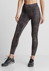 Czarne legginsy z wysokim stanem, z teksturowanym wzorem krokodylej skóry, elastyczny materiał i wzmocnione szwy. Posiadają logo na dolnej części nogawki.