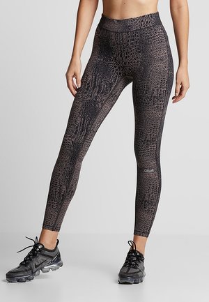 Czarne legginsy z wysokim stanem, z teksturowanym wzorem krokodylej skóry, elastyczny materiał i wzmocnione szwy. Posiadają logo na dolnej części nogawki.