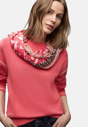 Suéter coral de manga larga con puños acanalados, combinado con una bufanda rosa estampada con diseños abstractos y varios tonos.