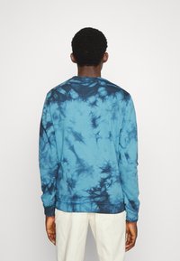Blue tie-dye sweatshirt with long sleeves, featuring a crew neck and a mix of lighter and darker blue patterns throughout.