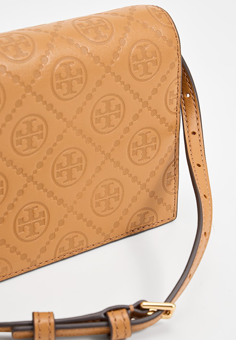 Hellbraune Leder-Crossbody-Tasche mit geprägtem Logo-Muster, rechteckiger Form und einem braunen Tragegurt mit Akzenten aus goldfarbenem Metall.