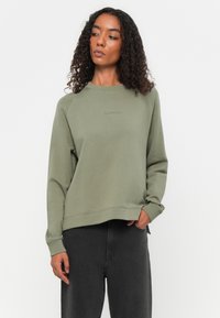 Olijfgroen sweatshirt met geribde manchetten en zoom, voorzien van een ronde hals en subtiele branding op de borst. Glad textuur en een relaxte pasvorm.