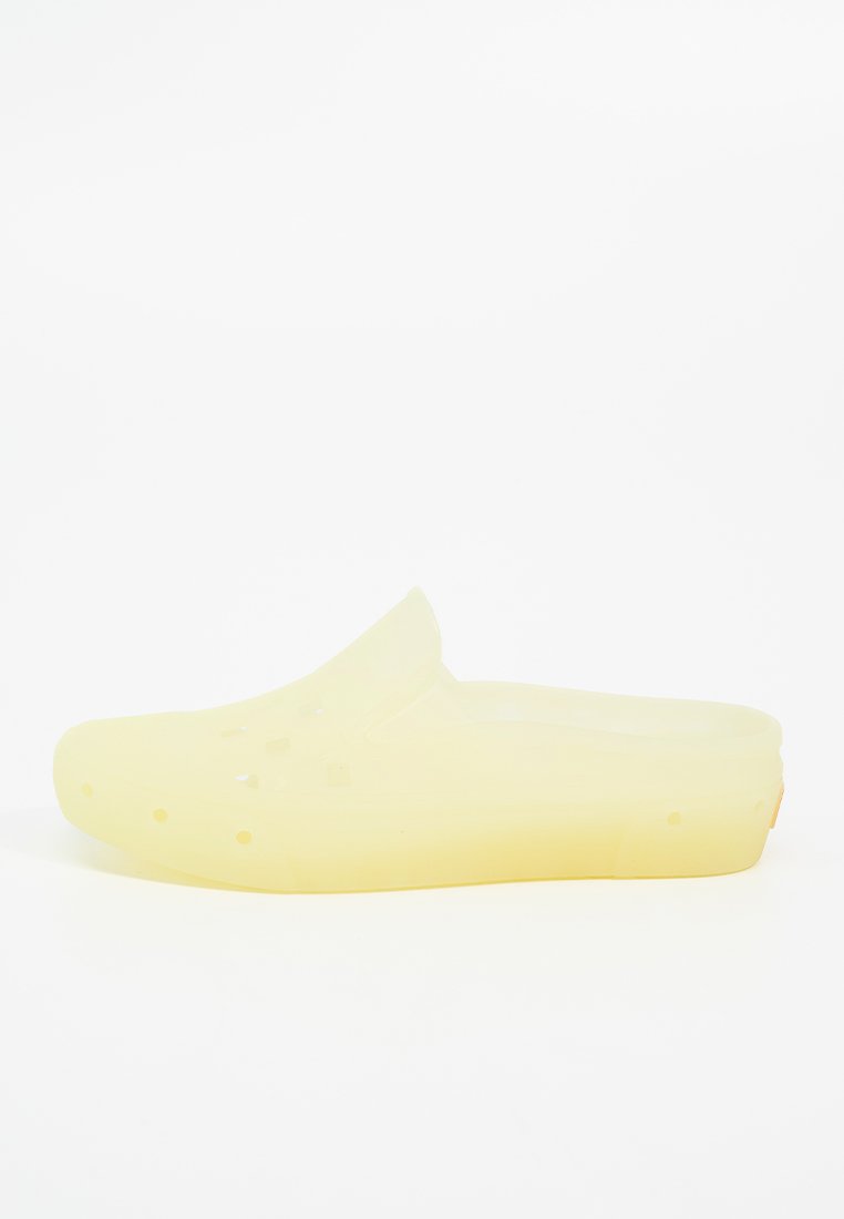 Sabot jaune translucide à dos ouvert, avec des trous de ventilation et un bout arrondi. Fabriqué en matériau flexible avec une finition lisse et mate.