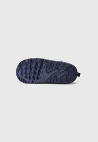 Tmavomodrá podrážka obuvi Nike s hlbokými dezénmi a viditeľným logom na jednoduchom bielom pozadí.